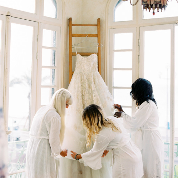 bridesmaids gathered around hanging wedding dress ball gown bridesmaids gathered around hanging wedding dress ball gown