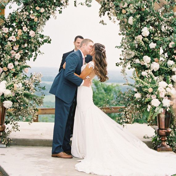 wedding couple kiss under floral archway wedding couple kiss under floral archway