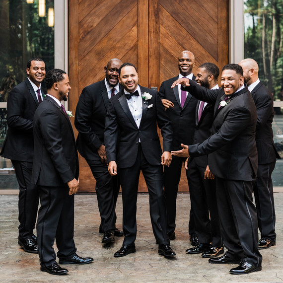 groom standing with groomsmen wearing black tuxedos groom standing with groomsmen wearing black tuxedos