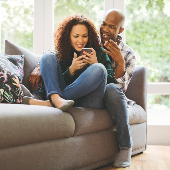 Couple Sitting on Couch Looking at Cell Phones Couple Sitting on Couch Looking at Cell Phones