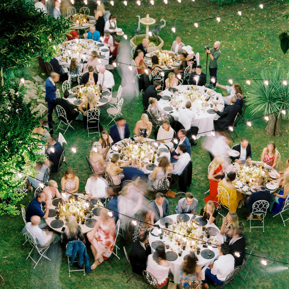 guests enjoying outdoor reception with hanging lights guests enjoying outdoor reception with hanging lights
