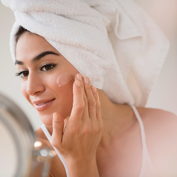 Woman Putting on Lotion Looking in the Mirror Woman Putting on Lotion Looking in the Mirror