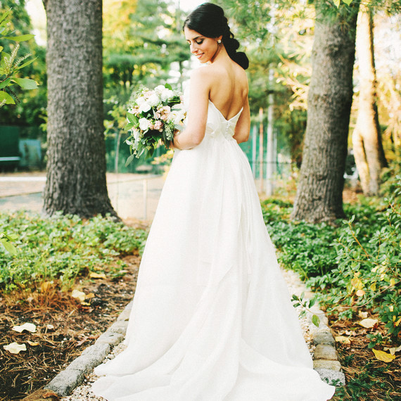 woman standing in garden in wedding dress- classic hair and makeup woman standing in garden in wedding dress- classic hair and makeup